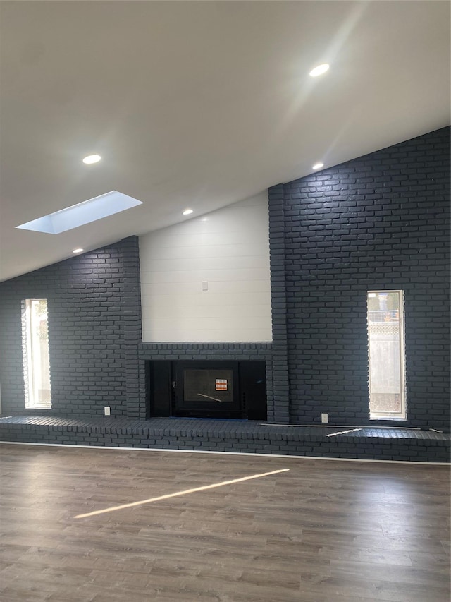 empty room with vaulted ceiling with skylight and hardwood / wood-style floors