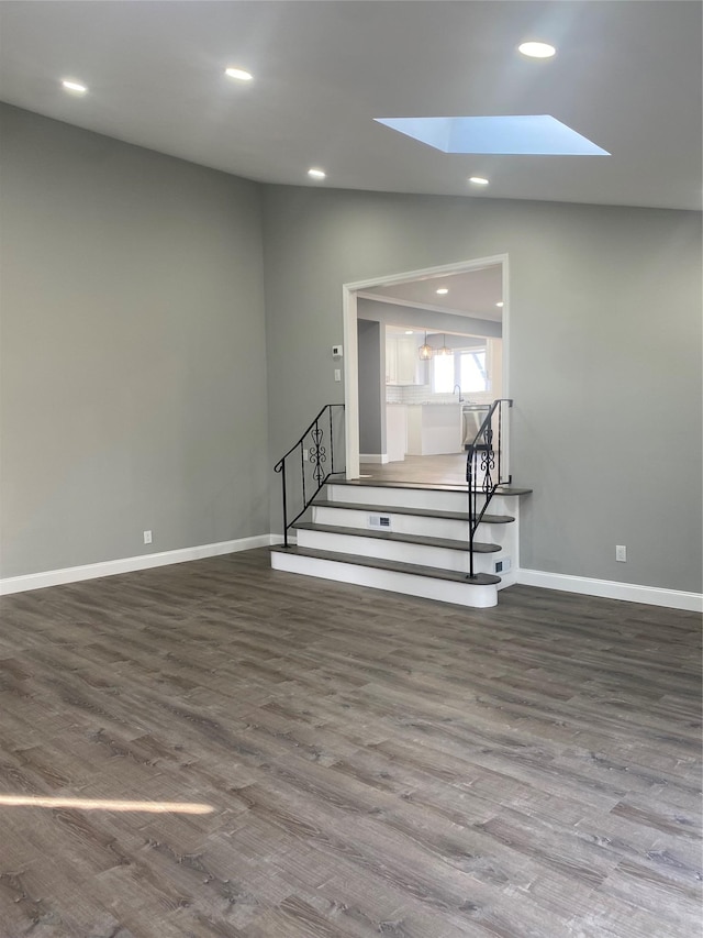 unfurnished living room with hardwood / wood-style flooring and a skylight