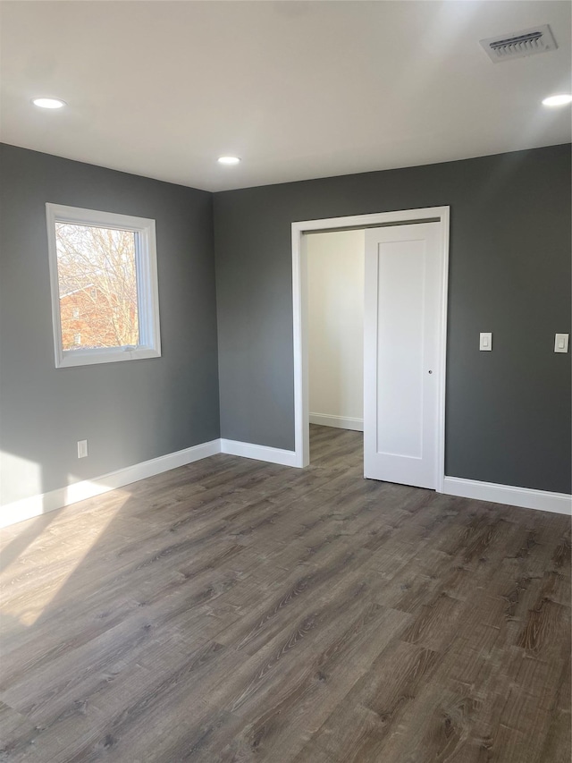 unfurnished bedroom with dark wood-type flooring and a closet