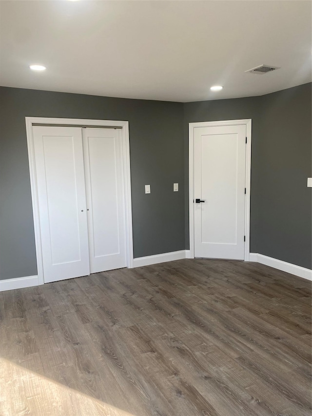 unfurnished bedroom with dark hardwood / wood-style flooring and a closet