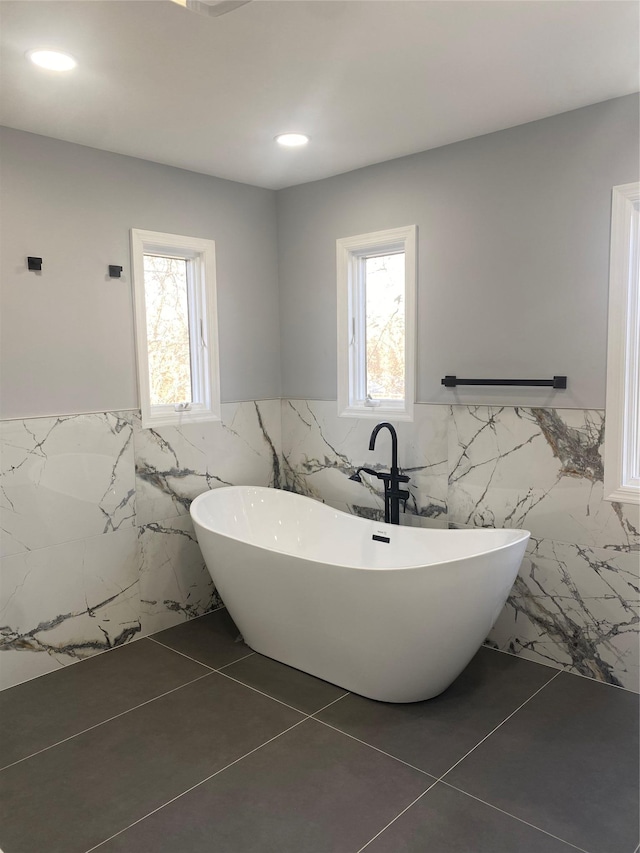 bathroom featuring tile patterned flooring, tile walls, and a washtub