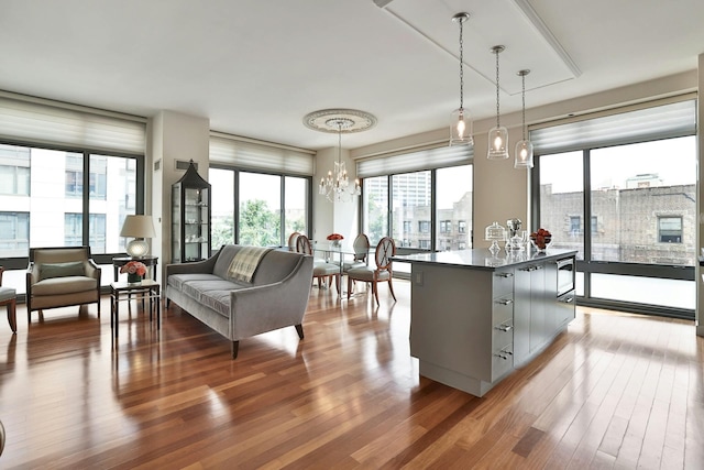 kitchen with pendant lighting, stainless steel microwave, an inviting chandelier, and hardwood / wood-style flooring