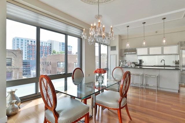 dining room featuring sink, a chandelier, and light hardwood / wood-style floors