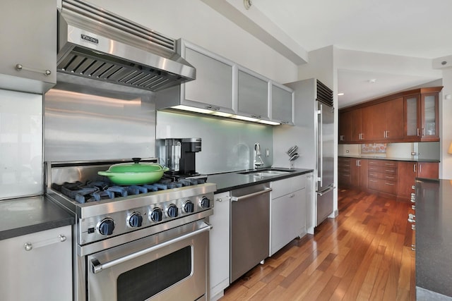 kitchen featuring high end appliances, sink, hardwood / wood-style floors, and extractor fan