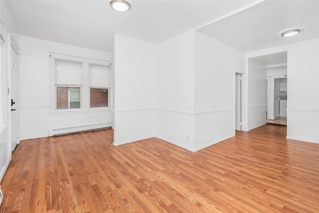 spare room with hardwood / wood-style floors and a baseboard heating unit