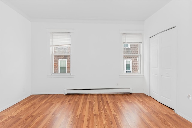 empty room with light wood-type flooring and baseboard heating