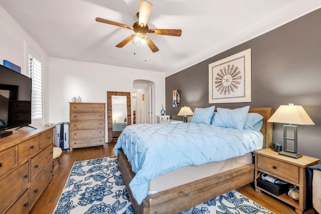 bedroom with arched walkways, dark wood-style floors, and a ceiling fan