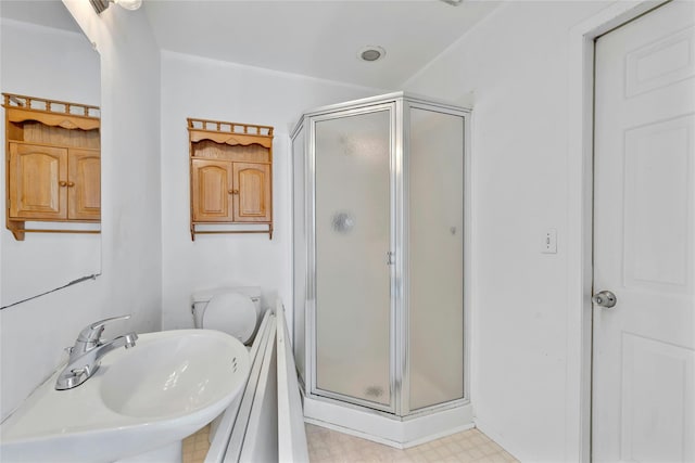 bathroom featuring an enclosed shower, sink, and toilet