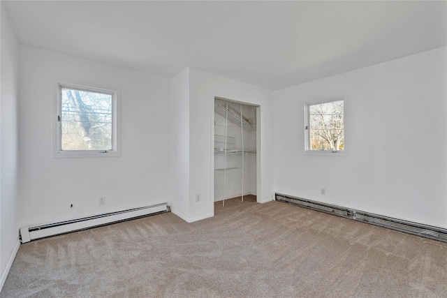 unfurnished bedroom featuring light colored carpet, multiple windows, and a baseboard heating unit