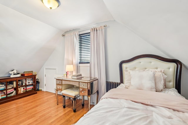 bedroom featuring wood-type flooring, lofted ceiling, and radiator