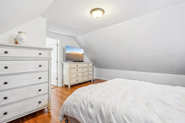 bedroom with vaulted ceiling and light wood-type flooring