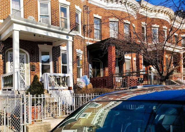 view of front of home featuring brick siding and fence