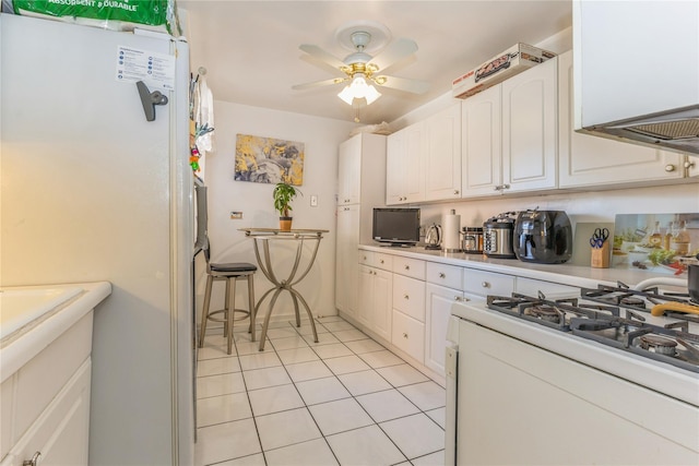 kitchen featuring light tile patterned flooring, ceiling fan, white gas stove, and white cabinets