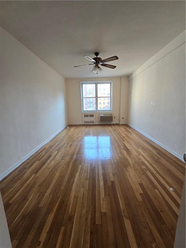 empty room with ceiling fan, radiator heating unit, and dark hardwood / wood-style floors