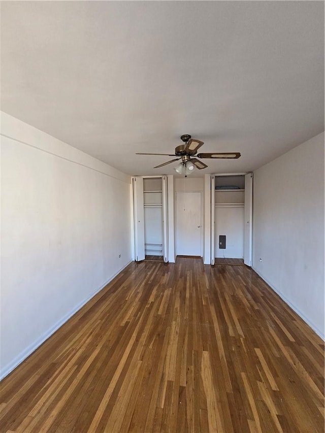 unfurnished bedroom with multiple closets, ceiling fan, and dark hardwood / wood-style flooring