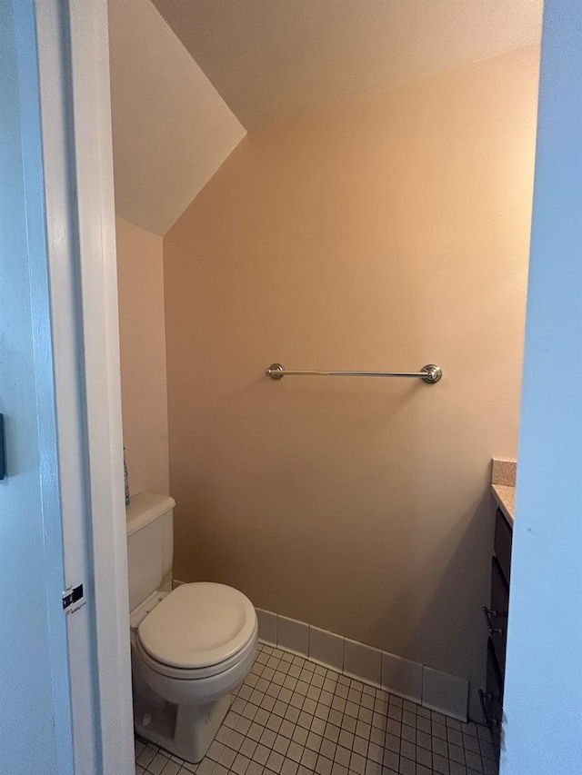 bathroom featuring lofted ceiling, tile patterned floors, toilet, and vanity