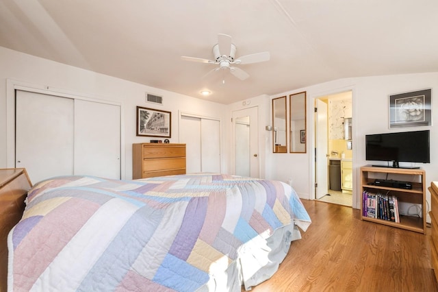 bedroom featuring lofted ceiling, ceiling fan, connected bathroom, light hardwood / wood-style floors, and multiple closets