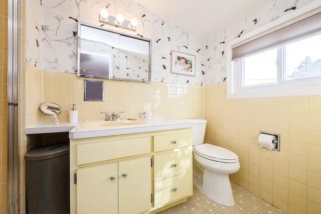 bathroom featuring vanity, toilet, tile patterned flooring, and tile walls