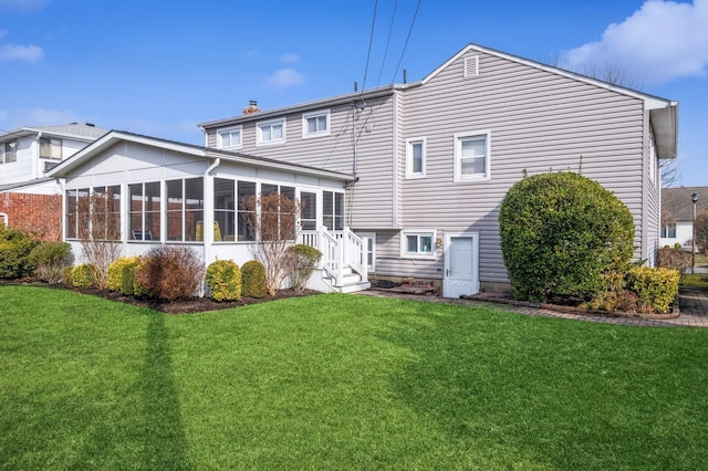 rear view of house featuring a sunroom and a lawn