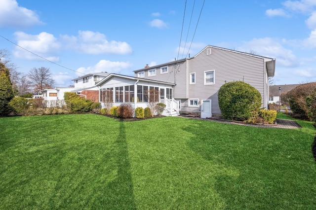 rear view of house with a lawn and a sunroom