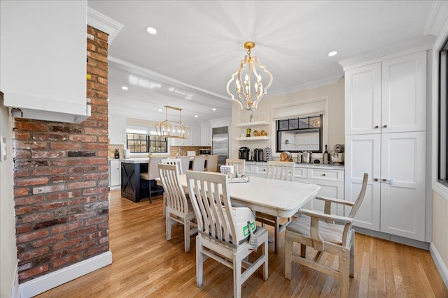 dining room with an inviting chandelier, crown molding, and light hardwood / wood-style floors