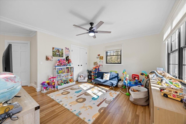 rec room with ornamental molding, hardwood / wood-style floors, and ceiling fan