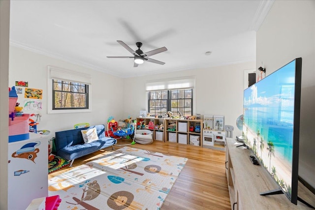 playroom with crown molding, light hardwood / wood-style flooring, and ceiling fan