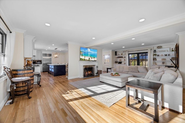 living room featuring crown molding, a brick fireplace, and light hardwood / wood-style flooring