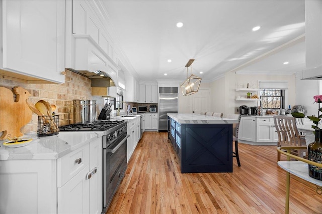 kitchen featuring a kitchen island, white cabinetry, premium appliances, hanging light fixtures, and light stone countertops