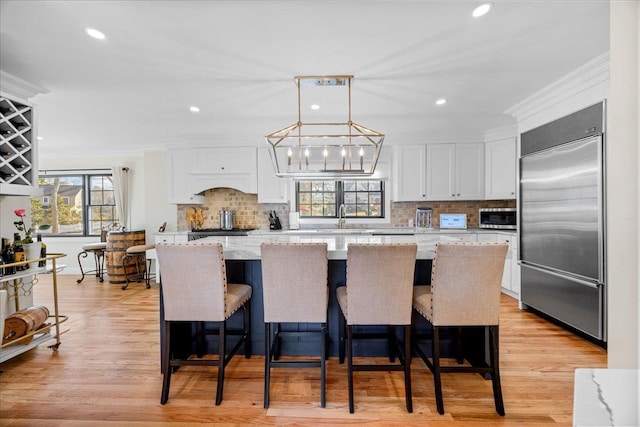 kitchen with a kitchen island, appliances with stainless steel finishes, pendant lighting, white cabinetry, and light stone countertops