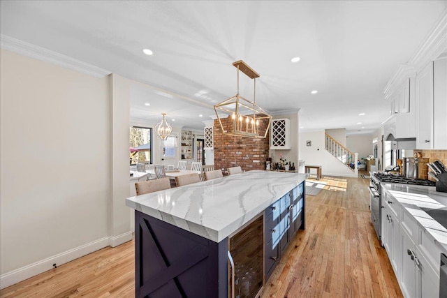 kitchen featuring hanging light fixtures, ornamental molding, a kitchen island, and white cabinets