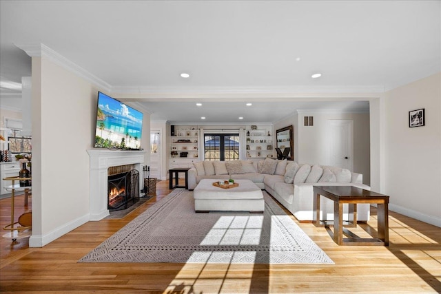 living room featuring crown molding, built in features, and light wood-type flooring