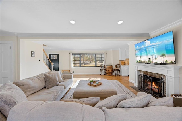 living room featuring crown molding, a high end fireplace, and light wood-type flooring