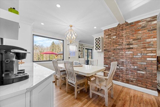 dining room with ornamental molding, brick wall, a notable chandelier, and light wood-type flooring