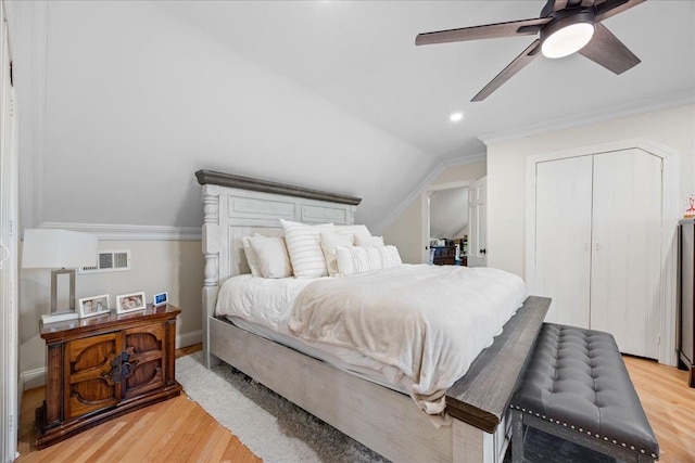 bedroom featuring ornamental molding, lofted ceiling, light hardwood / wood-style floors, and a closet