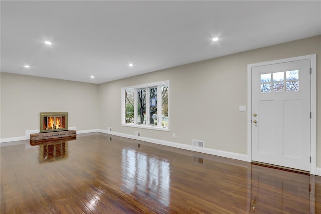 unfurnished living room with dark hardwood / wood-style flooring and a brick fireplace