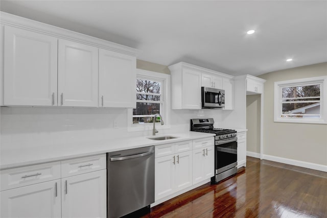 kitchen with stainless steel appliances, sink, white cabinets, and dark hardwood / wood-style floors