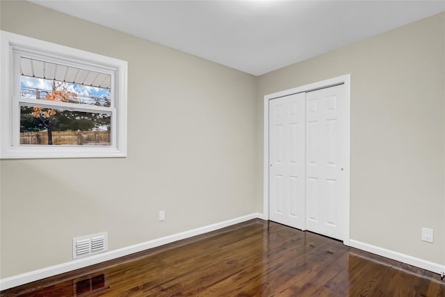 unfurnished bedroom with dark hardwood / wood-style flooring and a closet