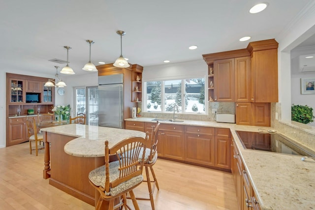 kitchen with a breakfast bar, pendant lighting, sink, decorative backsplash, and built in refrigerator