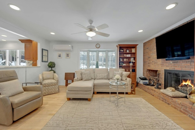 living room featuring an AC wall unit, a fireplace, ornamental molding, ceiling fan, and light wood-type flooring