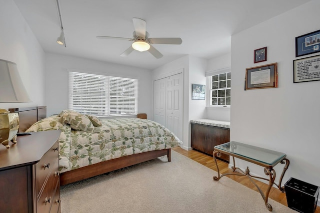 bedroom featuring multiple windows, light hardwood / wood-style floors, a closet, and ceiling fan