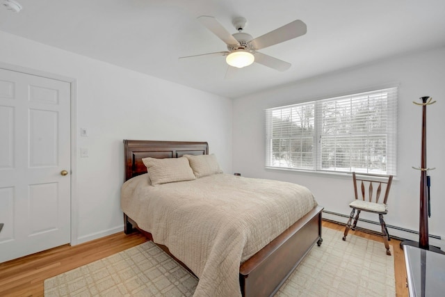 bedroom with baseboard heating, ceiling fan, and light hardwood / wood-style floors