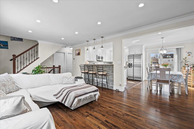 living room with crown molding, dark wood finished floors, recessed lighting, stairway, and an inviting chandelier