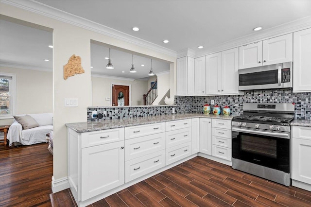 kitchen featuring stainless steel appliances, dark wood-type flooring, white cabinetry, open floor plan, and ornamental molding