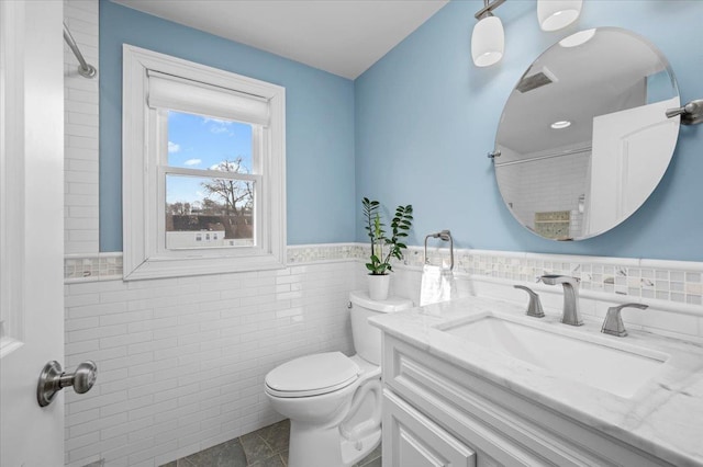 full bathroom featuring visible vents, toilet, a wainscoted wall, vanity, and tile walls