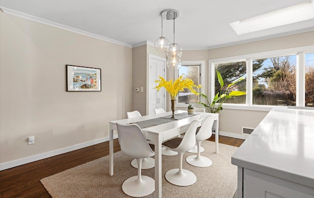 dining area featuring crown molding, dark wood-type flooring, and a skylight