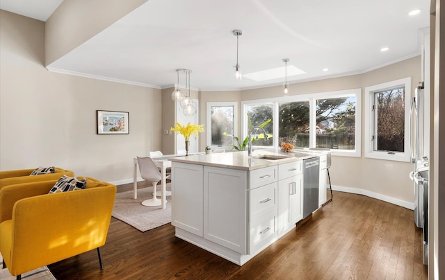 kitchen with appliances with stainless steel finishes, pendant lighting, white cabinetry, sink, and a center island with sink