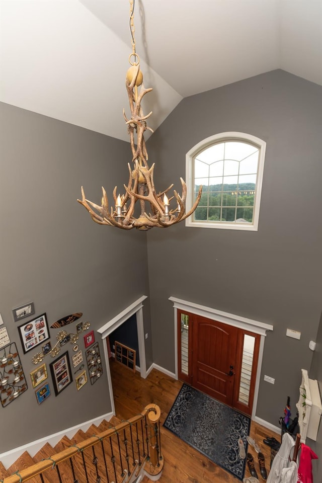 entryway with hardwood / wood-style flooring, vaulted ceiling, and a chandelier