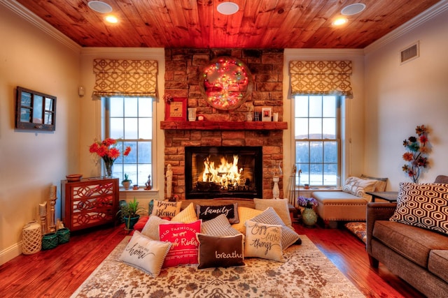 living room featuring hardwood / wood-style flooring, ornamental molding, a stone fireplace, and wood ceiling