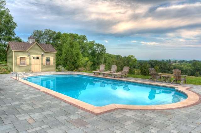 view of pool with a patio and an outdoor structure